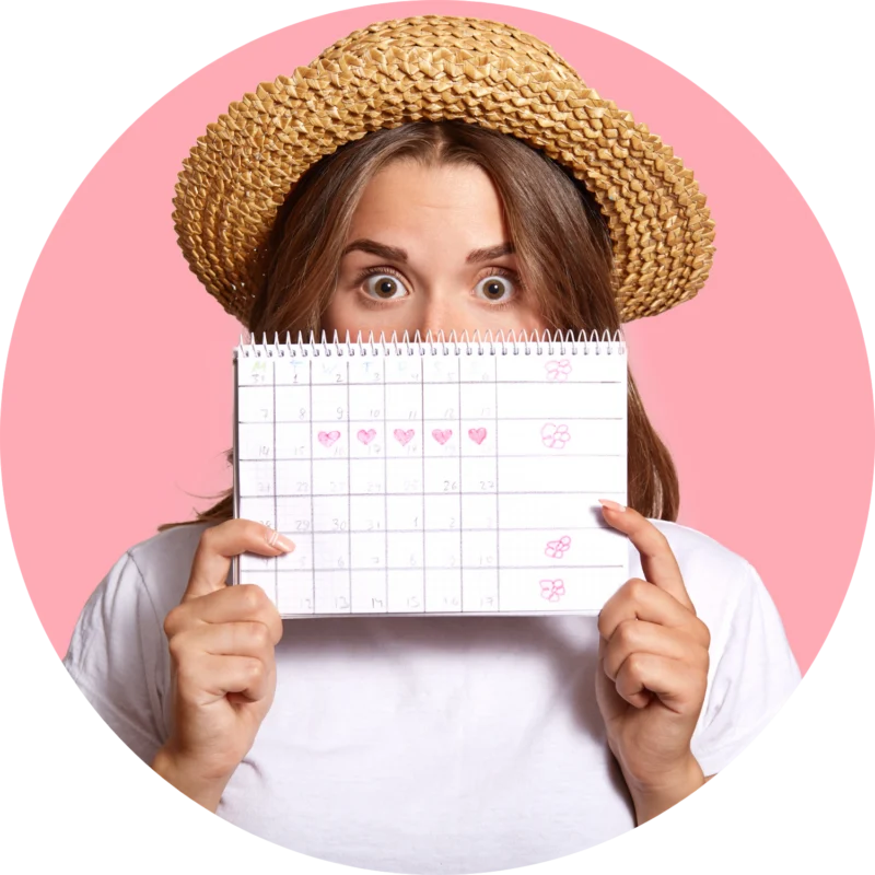 kobieta w kapeluszu trzyma w ręce kalendarz z cyklem miesiączkowym